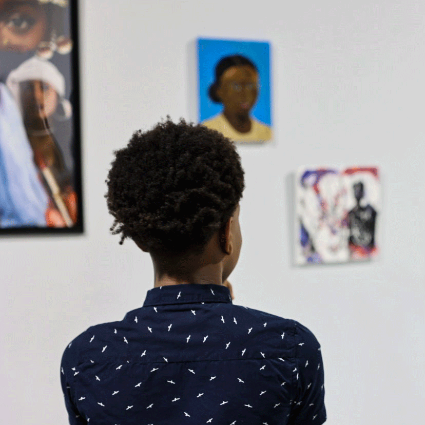 back of a young person looking at artwork on a wall